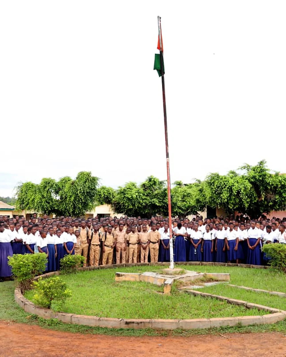 Élèves en uniforme rassemblés autour du mât du drapeau, Collège Assa de M'bahiakro